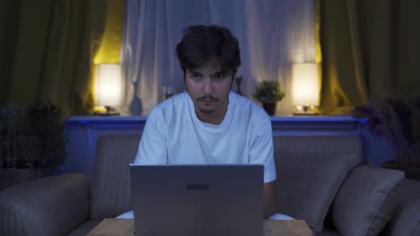 Man-focusing-on-computer-has-serious-expression.-At-home-at-night.